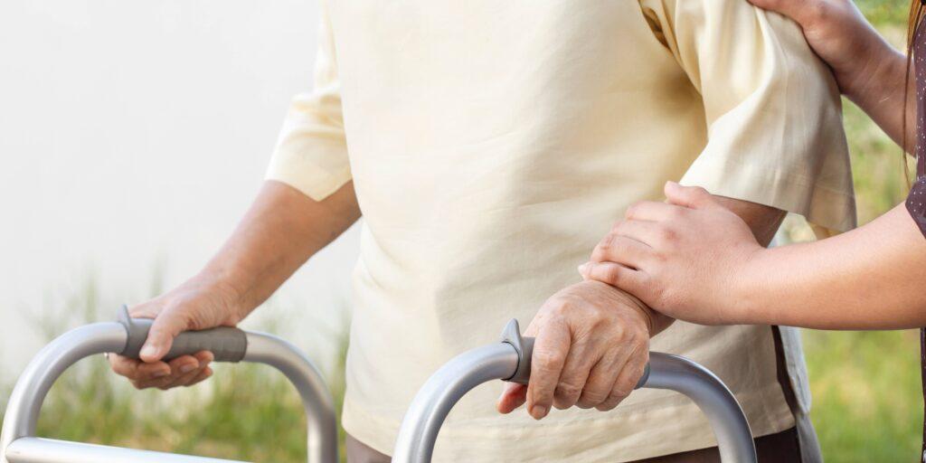 Person using a walker with the help of a caregiver. Elder care checklist