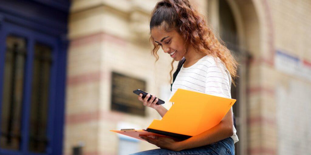 Young adult with smartphone and folder. Smartphone contract for teen at college.